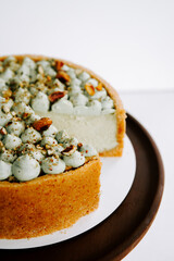 Delicious and creamy cake topped with mint frosting and nuts served on a wooden platter
