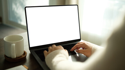 Hands typing on laptop with blank screen at home. Concept of remote work, technology, and online business.