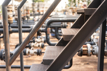 An overpass walkway across the production pipeline at the petrochemical and refinery plant. Industrial work place, close-up and selective focus.
