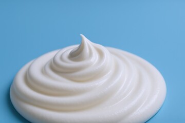 Swirl of Whipped Cream on a Blue Background, Ideal for Dessert Toppings and Culinary Applications