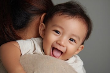 Loving moment shared between a smiling baby and mother as the little one rests comfortably on her shoulder
