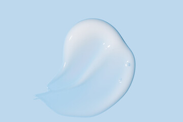 Cosmetic product smear white moisturizing lotion isolated on blue, squeezed out and smeared portion of skincare cream product testing.