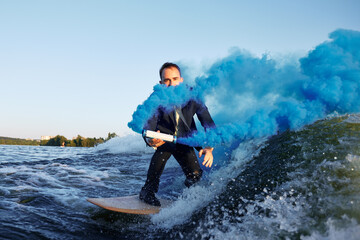 Man in Suit Surfs on Water With Vivid Blue Smoke Effects