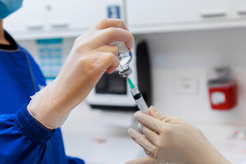 Healthcare professionals preparing syringe with vaccine from vial in clinical setting