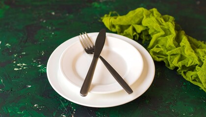 Empty plates and cutlery on a dark green textured surface