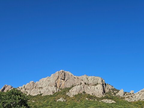 Majestic rocky mountain against a vast, clear blue sky. Perfect for travel themes, motivational content, or as a website banner with ample copy space for text.