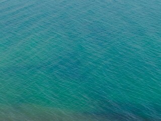 Aerial view of a calm, turquoise sea. A serene and minimalist background perfect for travel, wellness, or abstract design concepts.