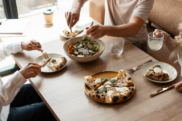Friends enjoying pizza and salad at restaurant table