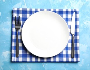 Empty white plate on blue checkered napkin
