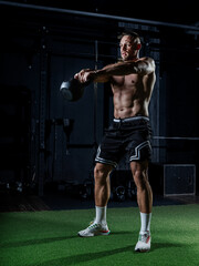 Muscular man training with weights. Brutal strong athletic men pumping up muscles workout in dark gym.