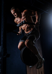 Muscular man training with weights. Brutal strong athletic men pumping up muscles workout in dark gym.