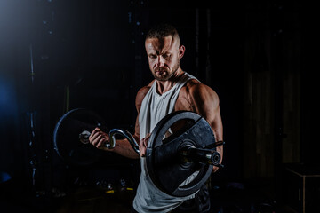 Muscular man having training with weights. Strong athletic man does workout. Concept bodybuilder doing exercises in gym.