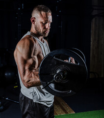 Muscular man having training with weights. Strong athletic man does workout. Concept bodybuilder doing exercises in gym.