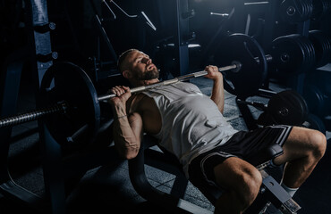 Muscular man having training with weights. Strong athletic man does workout. Concept bodybuilder doing exercises in gym.