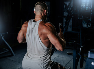 Muscular man training with weights. Brutal strong athletic men pumping up muscles workout in dark gym.