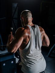 Muscular man having training with weights. Strong athletic man does workout. Concept bodybuilder doing exercises in gym.