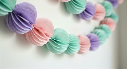 Obraz premium Garland of pastel paper rosettes in soft purple, pink, mint, and blue, strung in a neat pattern to bring a gentle, festive charm to any celebration