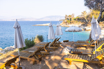 Obraz na płótnie Canvas Premium wooden sun loungers with elegant umbrellas positioned on a rocky Mediterranean shoreline at golden hour offering exclusive beachfront relaxation with stunning sea views distant island vistas
