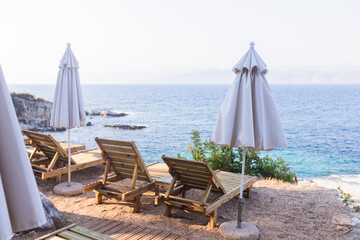 Tranquil and sunny seaside resort beach with rows of elegant wooden sun loungers and matching white umbrellas, perfect for a relaxing summer vacation.