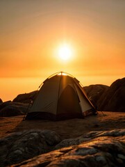 Camping tent sitting alone on a rocky terrain at dawn with sun rising behind it