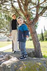 Child balancing on rock with parent in park