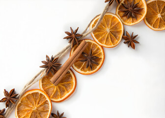 Dried orange slices and star anise with cinnamon sticks arranged on a white surface