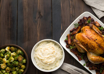 Roasted chicken dinner featuring mashed potatoes and brussel sprouts on wooden table top