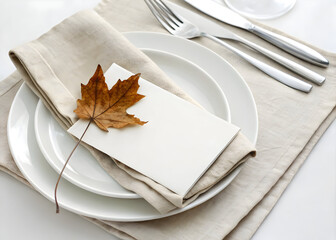 Elegant table setting with white plates, linen napkin, silverware, and autumn leaf decor