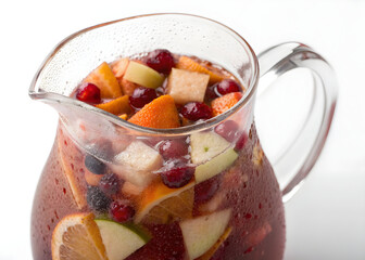 Refreshing fruit sangria in a glass pitcher with apples oranges and berries beverage drink