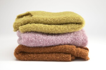 Stack of cozy knitted sweaters in autumn colors on white background