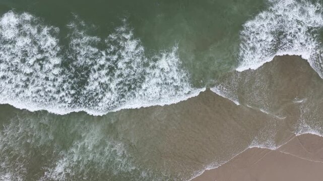 Seen from a bird's eye view, mellow waves wash onto an empty beach on Cape Cod, Massachusetts. 