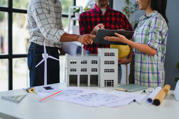 Engineers analyzing building model and using tablet during meeting