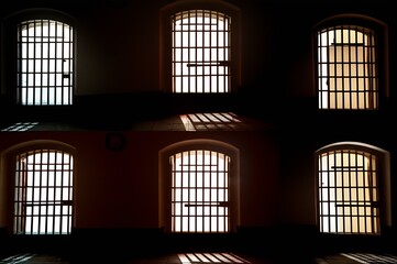 Eerie asylum interior with spooky barred windows casting flickering lights, creating an unsettling atmosphere of dread and suspense.