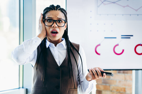 Young Surprised Businesswoman Holding a Smartphone in a Modern Office Environment - Powered by Adobe