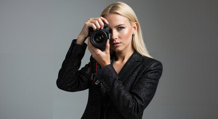 Young woman holding camera and taking photo in studio setting  