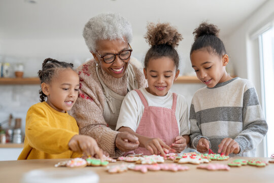 grandmother and her grandchildren are joyfully decorating gingerbread cookies together