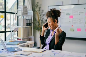 Excited african american businesswoman receiving good news on phone in office
