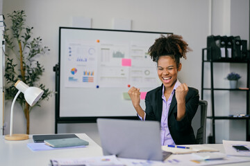 Excited african american businesswoman celebrating success at office desk