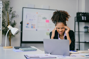 Stressed African American businesswoman suffering from headache at office desk