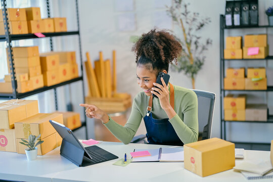 Smiling african american woman managing online store using tablet and smartphone