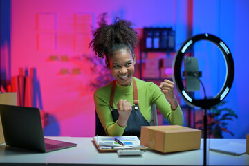 Happy african american business woman live streaming, selling online, working from home