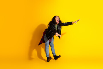 Young man with long black hair gesturing joyfully on a vibrant yellow background wearing stylish...