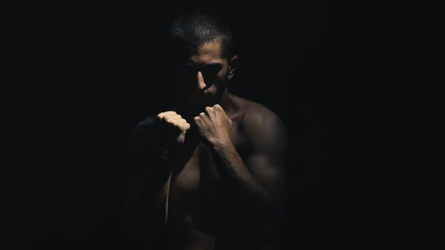 African American man in a dramatic lighting setup, showcasing intense focus and readiness in a boxing stance, emphasizing strength and determination in a powerful motion sequence