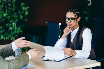 Professional businesswoman reviewing document in office setting while engaged in a focused...