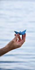 A blue paper boat on the water, a symbol of hope and freedom. The image evokes the concept of mental health, the inner journey, and the search for peace and serenity. Copy Space.