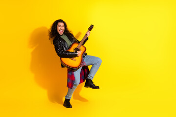 Fototapeta premium Attractive stylish man with guitar in vibrant yellow setting showcasing trendy fashion and joyful expression while playing