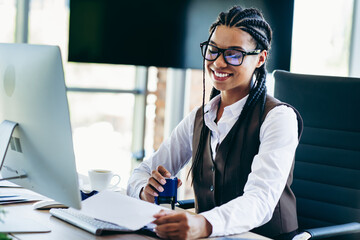 Confident female professional using computer while working in a modern office environment with a bright smile