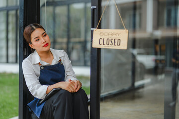 Sad waitress sitting outside closed cafe looking worried about business