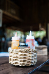 Ketchup and crushed red pepper flakes in pepper shakers in basket