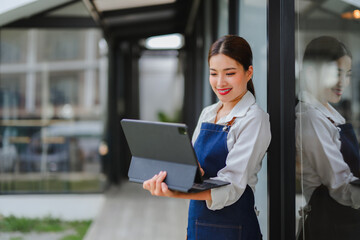 Smiling waitress using tablet managing online orders in front of her coffee shop